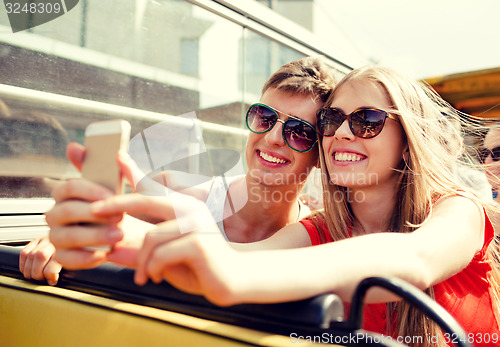 Image of smiling couple with smartphone making selfie