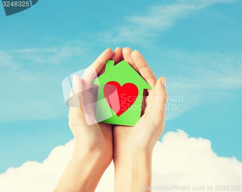 Image of hands holding green paper house