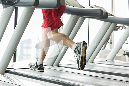 Image of close up of male legs running on treadmill in gym