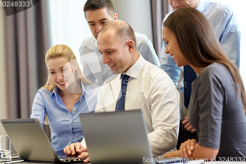 Image of smiling businesspeople with laptops in office