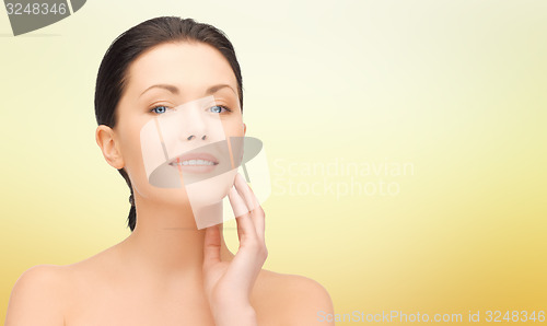 Image of beautiful young woman touching her face