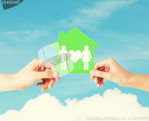 Image of hands holding green house with family