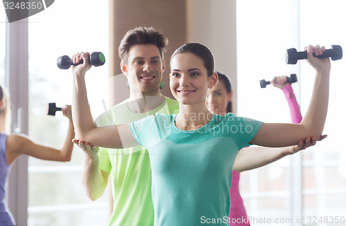 Image of happy women and trainer with dumbbells in gym