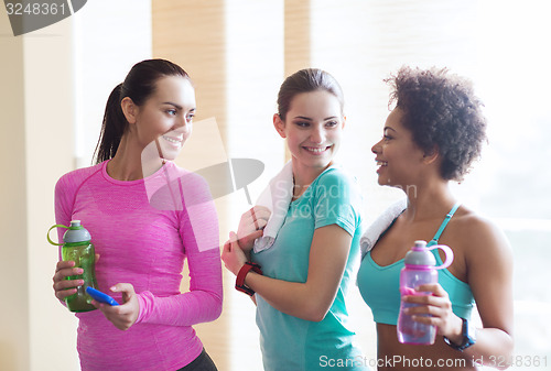 Image of happy women with bottles of water in gym