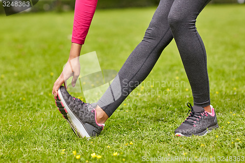 Image of close up of woman stretching leg outdoors