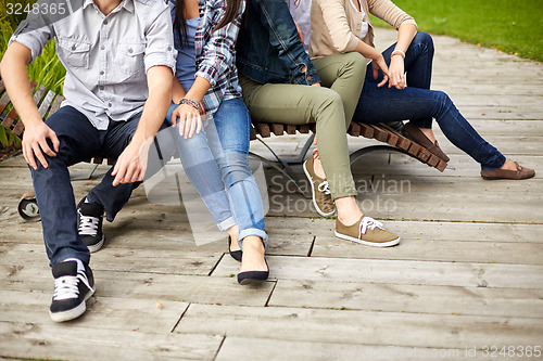 Image of close up of many legs sitting on bench at park