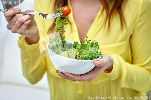 Image of close up of young woman eating salad at home