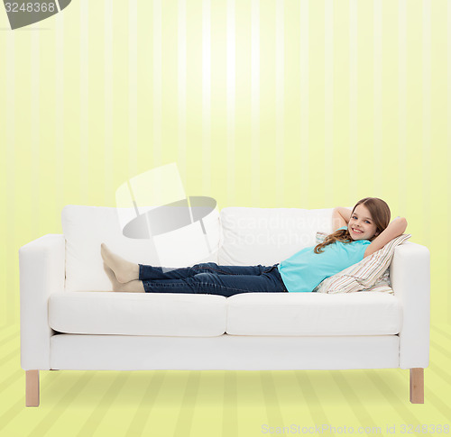 Image of smiling little girl lying on sofa