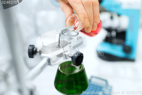 Image of close up of scientist filling test tubes in lab