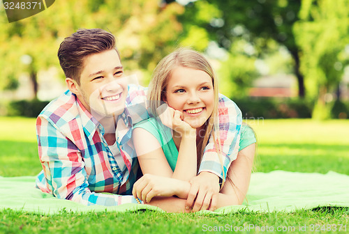 Image of smiling couple lying on blanket in park