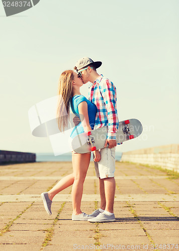 Image of couple with skateboard kissing outdoors