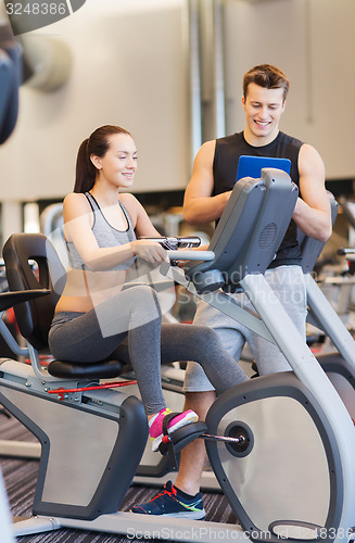 Image of happy woman with trainer on exercise bike in gym