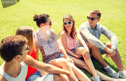 Image of group of smiling friends outdoors sitting in park