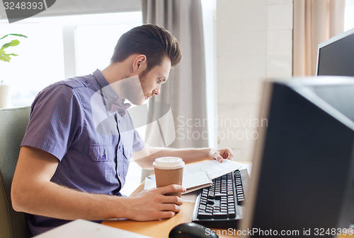 Image of creative male worker drinking coffee and reading