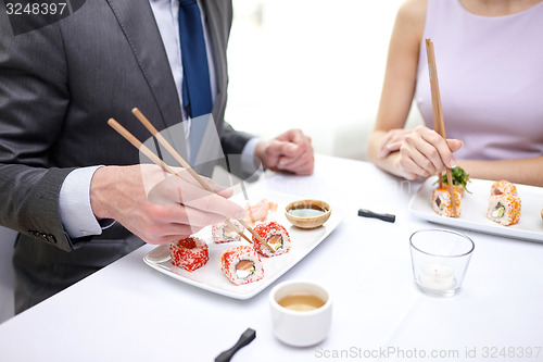 Image of close up of couple eating sushi at restaurant