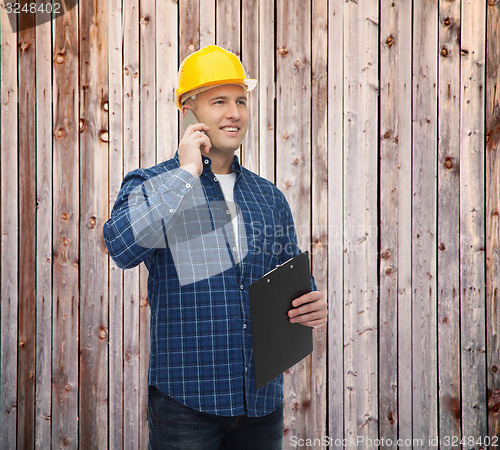 Image of smiling male builder in helmet with clipboard