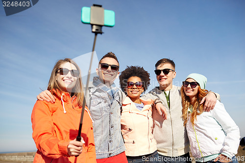 Image of smiling friends taking selfie with smartphone