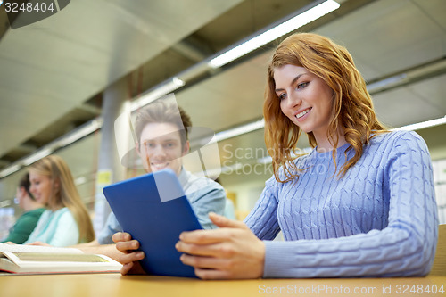 Image of happy students with tablet pc in library