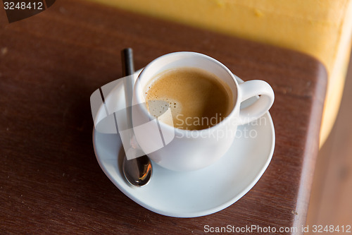 Image of cup of black coffee with spoon and saucer on table