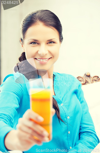 Image of woman holding glass of orange juice