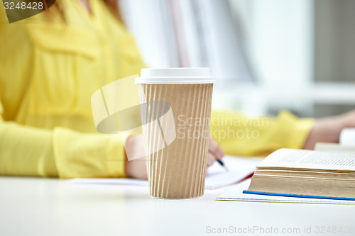 Image of close up of female hands with books and coffee