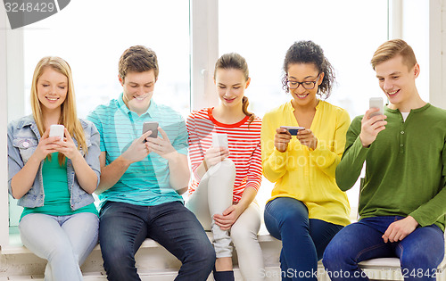 Image of smiling students with smartphone texting at school
