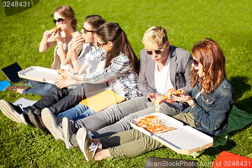 Image of group of teenage students eating pizza on grass