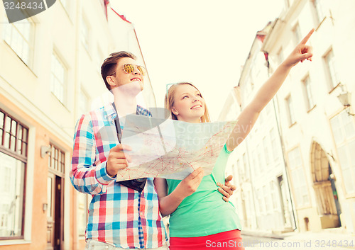 Image of smiling couple with map and photo camera in city