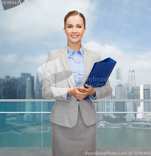 Image of smiling businesswoman holding folder over city