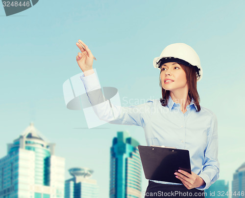 Image of smiling businesswoman in helmet with clipboard