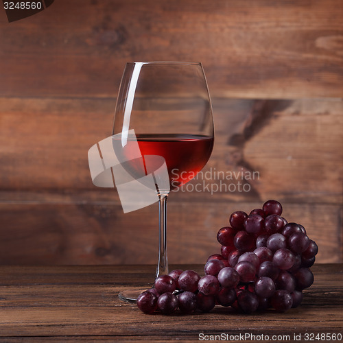 Image of Red wine in glass with grape on wood