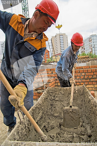 Image of Workers knead solution for bricklayers