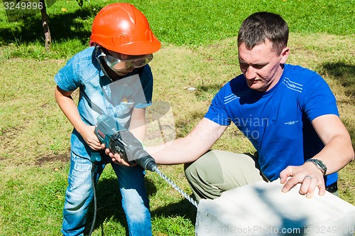 Image of A child learns to work with electric drill