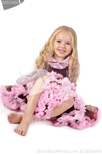 Image of Happy girl in tutu skirt sitting on the floor