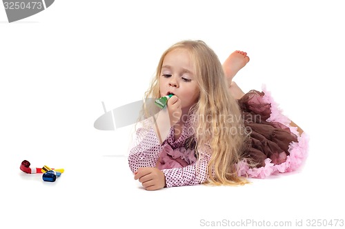 Image of Little baby girl in tutu skirt using party blower