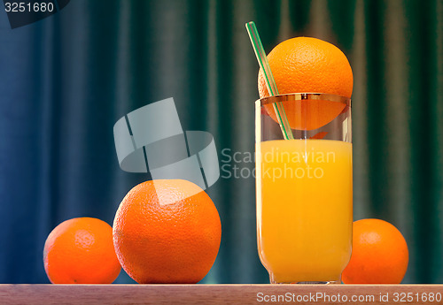 Image of Orange juice in a glass and oranges on the table.