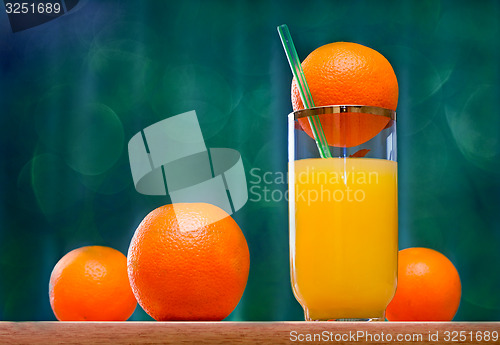 Image of Orange juice in a glass and oranges on the table.