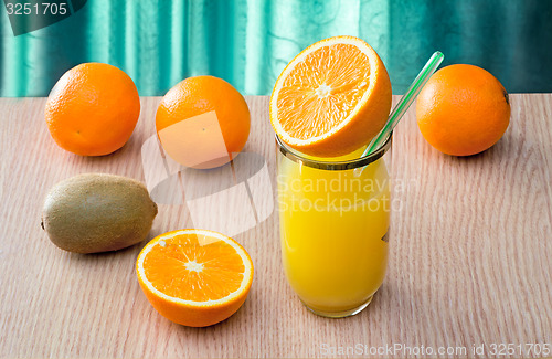 Image of Orange juice in a glass and oranges on the table.