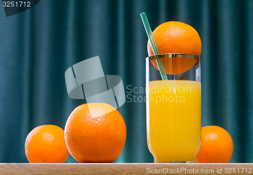 Image of Orange juice in a glass and oranges on the table.