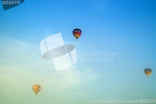 Image of three hot air balloons flying above morning fog