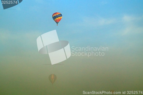 Image of three hot air balloons flying through morning fog