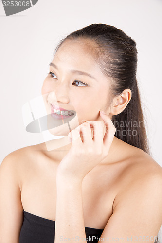 Image of Beautiful young Asian girl with one hand on face