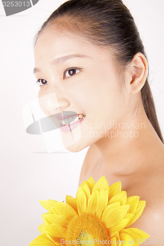 Image of Beautiful young Asian girl with bright yellow sunflower