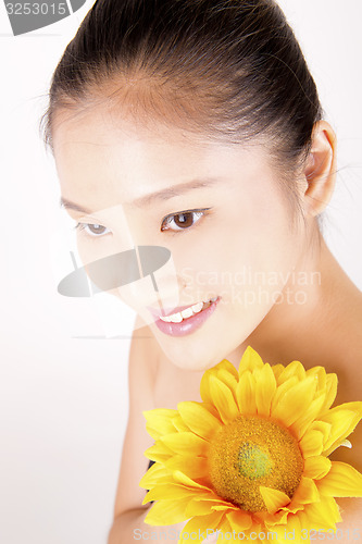 Image of Beautiful young Asian girl with bright yellow sunflower