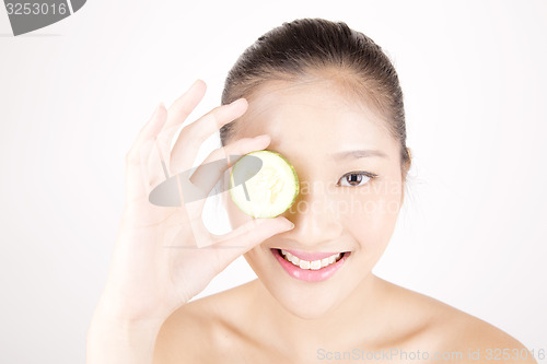 Image of Beautiful young Asian girl holding cucumber slice over face