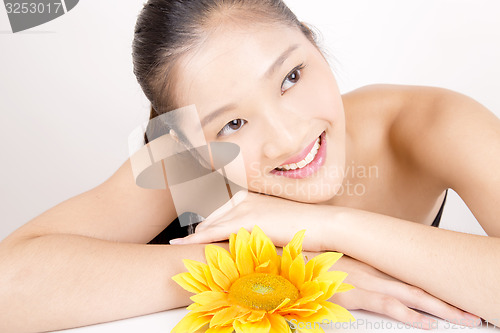 Image of Beautiful young Asian girl with bright yellow sunflower