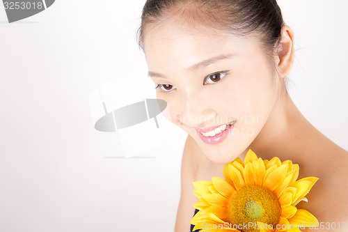 Image of Beautiful young Asian girl with bright yellow sunflower