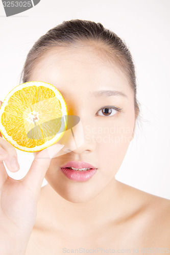 Image of Beautiful young Asian girl holding orange slice over face