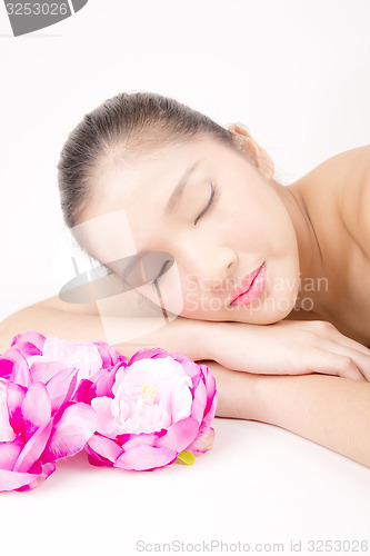 Image of Beautiful young Asian girl lying down with red peony flowers