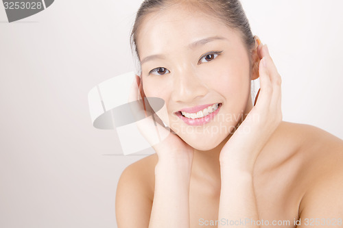 Image of Beautiful young Asian girl with both hands on face